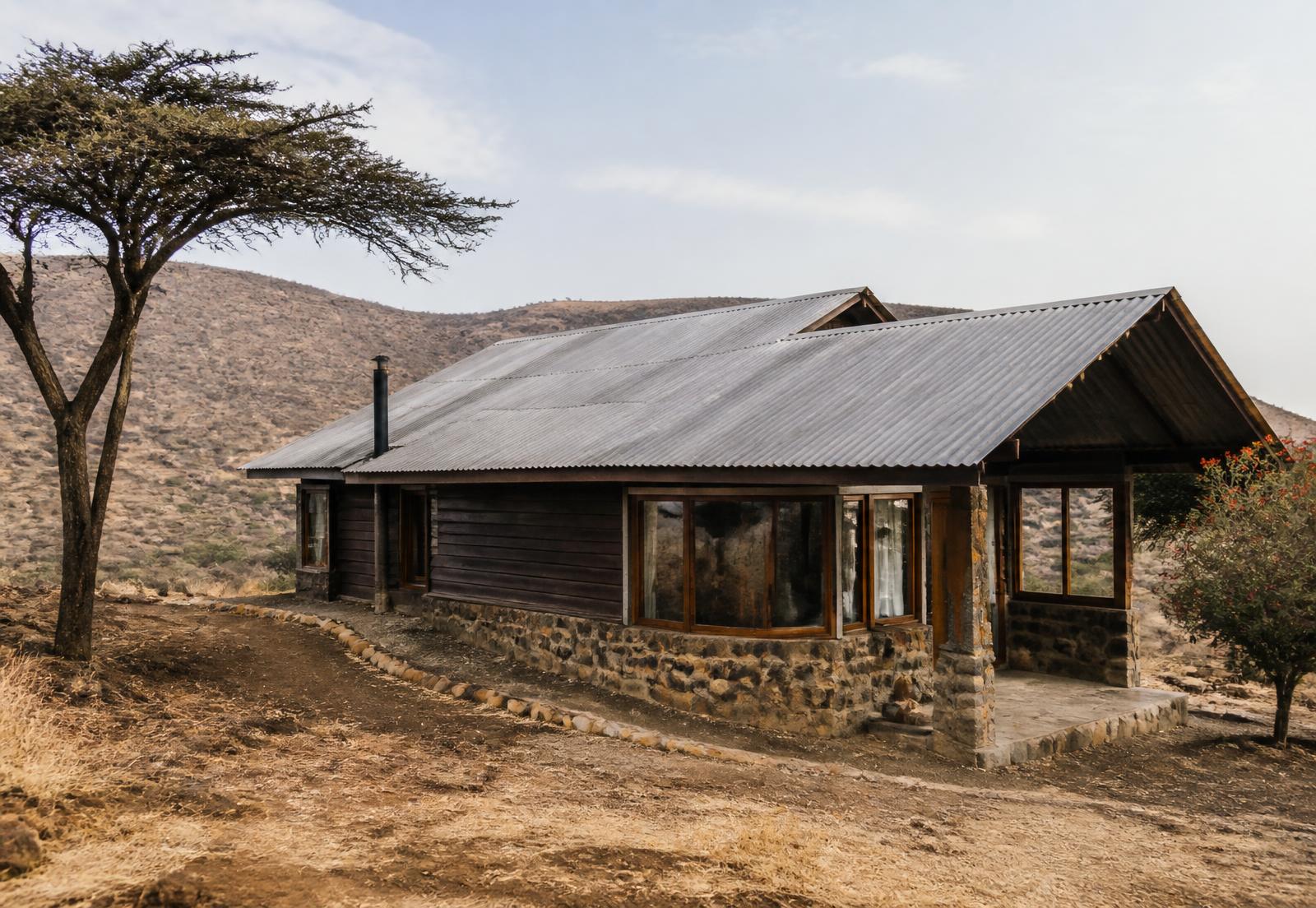 Timber and stone cottage on a Kenyan hillside, photographed in late afternoon light